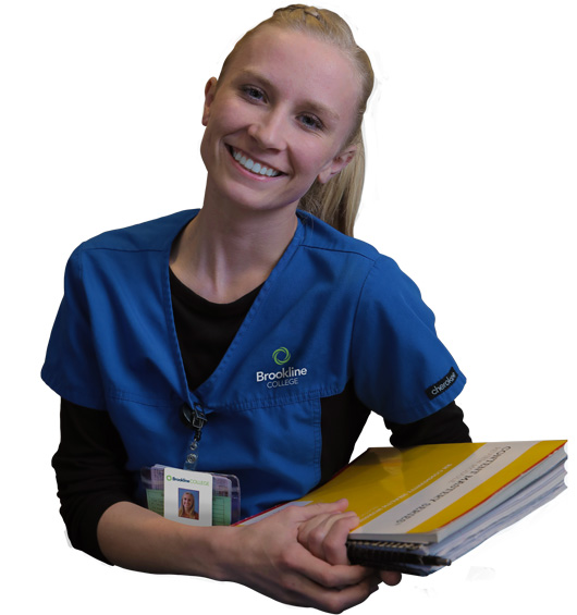 Nursing student in blue scrubs holding textbooks