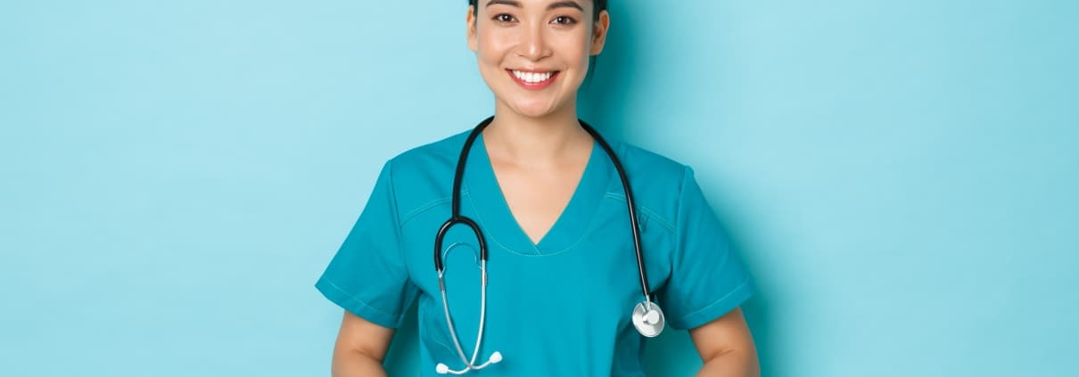 Asian nurse standing against a blue backdrop