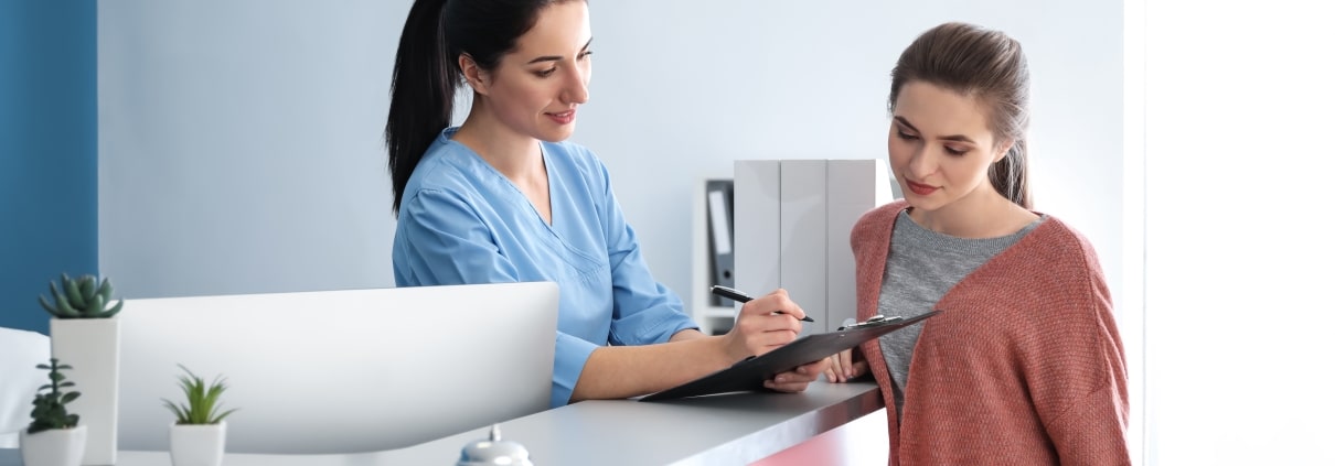 Young medical receptionist with a female patient