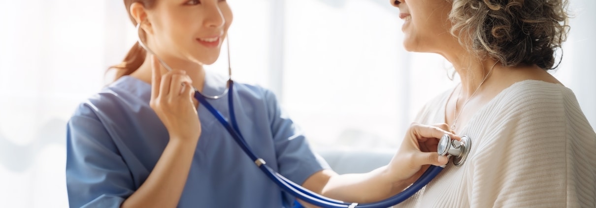 Nurse using a stethoscope on an elderly patient