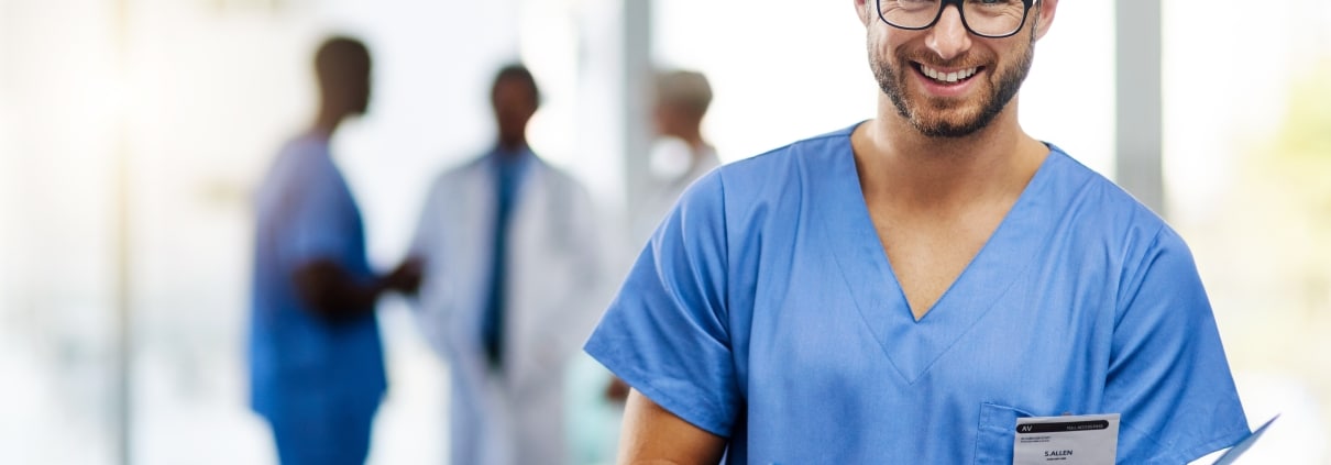 Smiling male nurse with glasses holding a patient's chart