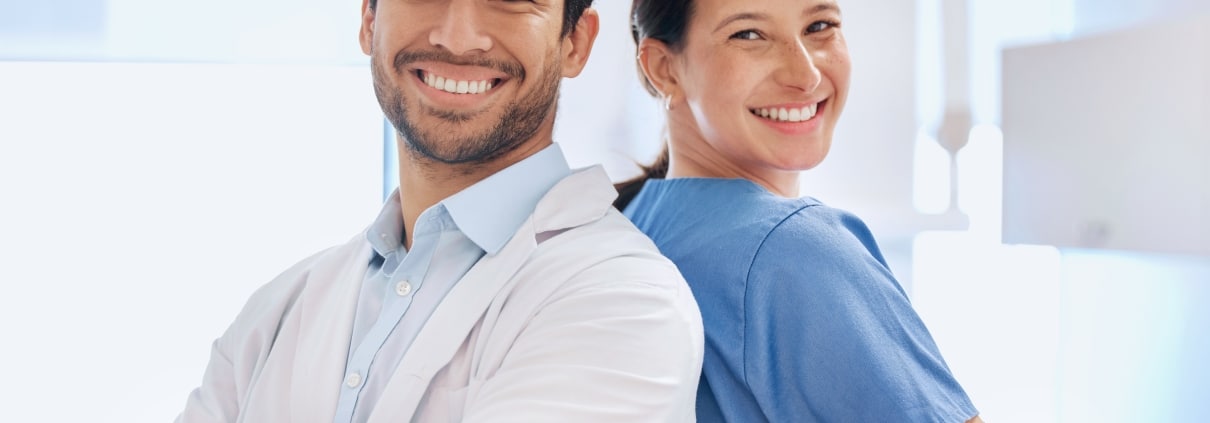 Two medical professionals smiling back to back with their arms crossed