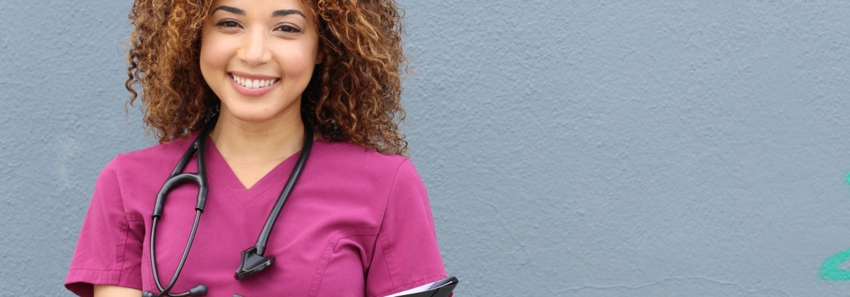 Smiling African-American nurse in pink scrubs
